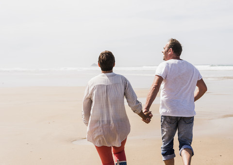 Älteres Paar läuft am Strand, lizenzfreies Stockfoto