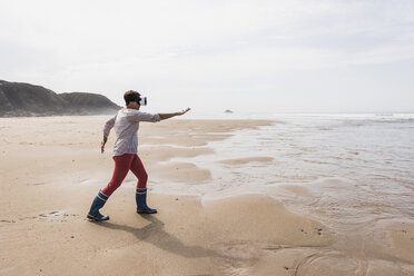 Reife Frau am Strand mit VR-Brille - UUF08585