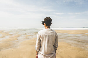 Mature woman standing on the beach wearing VR glasses - UUF08587