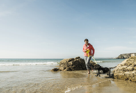 Mature woman walking with dog at the sea - UUF08606