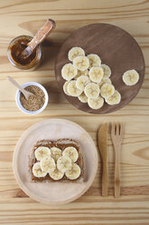 Toast with Dulce de Leche, banana slices and sesame seeds on wooden plate and table - RTBF00376