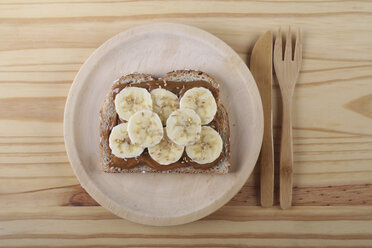 Toast with Dulce de Leche, banana slices and sesame seeds on wooden plate and table - RTBF00377