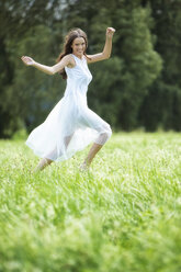 Glückliche Frau im weißen Sommerkleid auf einer Wiese - MAEF12020