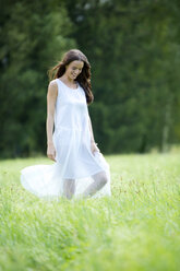 Glückliche Frau im weißen Sommerkleid auf einer Wiese - MAEF12022