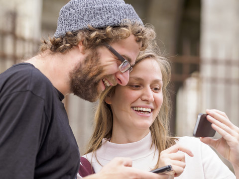 Lächelndes junges Paar schaut auf Smartphone, lizenzfreies Stockfoto