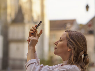 Frankreich, Chartres, junge Frau fotografiert mit Smartphone vor Notre-Dame de Chartres - LAF01730