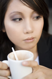 Junge Frau mit einer Tasse Kaffee beobachtet etwas - NGF00364