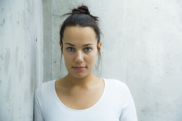 Portrait of young woman leaning against concrete wall - NGF00373