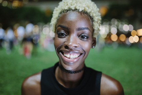 Porträt einer lächelnden jungen Frau in einem Park bei Nacht, lizenzfreies Stockfoto