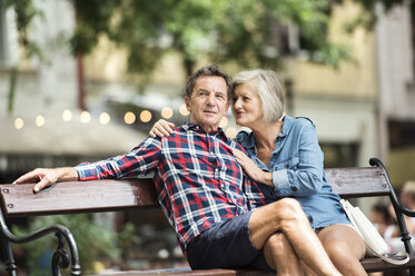 Senior couple sitting on bench watching something - HAPF00893