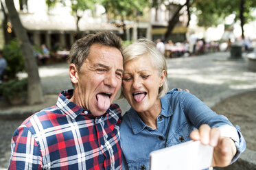 Älteres Paar zieht lustige Grimassen, während es ein Selfie mit dem Smartphone macht - HAPF00912