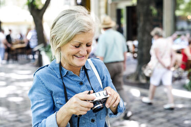 Lächelnde ältere Frau mit Kamera - HAPF00939
