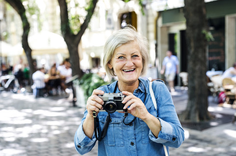 Porträt einer lächelnden älteren Frau mit Kamera, lizenzfreies Stockfoto
