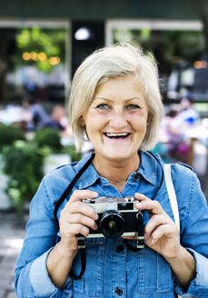 Porträt einer glücklichen älteren Frau mit Kamera - HAPF00942