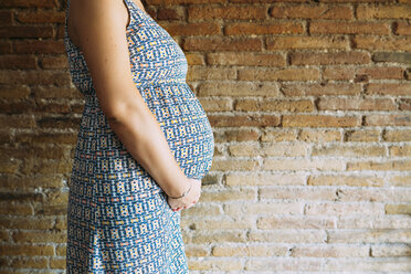 Schwangere Frau, die an einer Mauer steht - GEMF01015