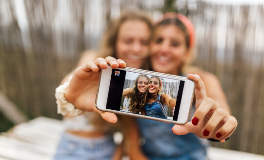 Selfie von zwei lächelnden Teenagern auf dem Display eines Smartphones - MGOF02444