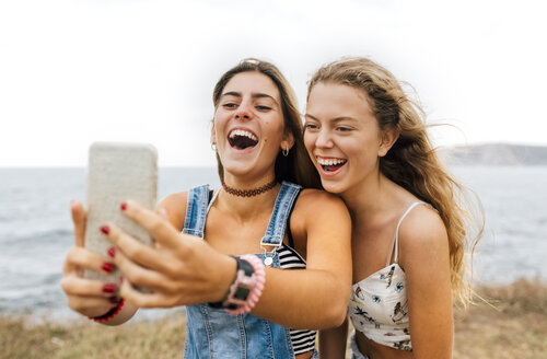 Zwei beste Freunde machen ein Selfie mit Smartphone an der Küste - MGOF02448