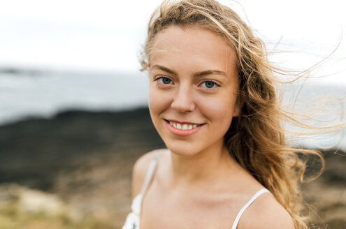 Porträt eines lächelnden blonden Teenagers an der Küste - MGOF02452