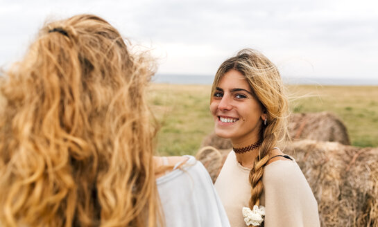 Lächelndes blondes Teenager-Mädchen und ihre beste Freundin an der Küste - MGOF02457
