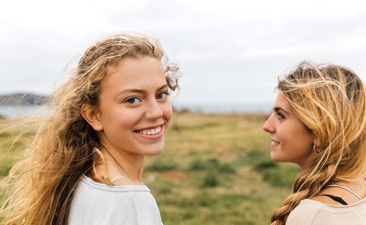 Lächelndes blondes Teenager-Mädchen und ihre beste Freundin an der Küste - MGOF02458