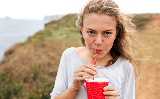 Porträt eines Teenagers mit Getränk an der Küste - MGOF02461