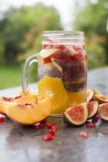 Ein Glas Wasser mit Orangenscheiben, Feigen, Granatapfelkernen, Nektarinen und Pflaumen - SARF02907