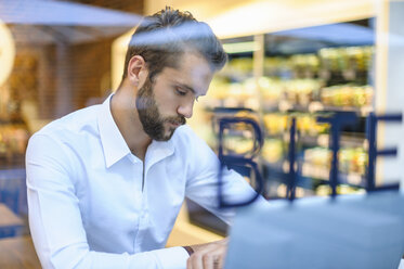 Geschäftsmann mit Laptop in einem Café, der die Zeit überprüft - DIGF01225