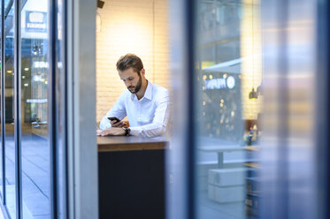 Geschäftsmann benutzt Mobiltelefon in einem Café - DIGF01228