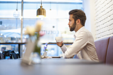 Businessman sitting in a cafe with cup of coffee - DIGF01243