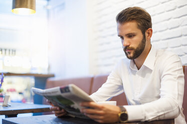 Businessman sitting in a cafe reading newspaper - DIGF01244