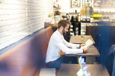 Geschäftsmann sitzt in einem Café und liest Zeitung - DIGF01245