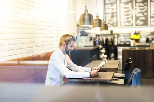 Geschäftsmann sitzt in einem Café und liest Zeitung - DIGF01246