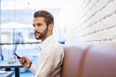 Geschäftsmann mit Mobiltelefon in einem Cafe - DIGF01253