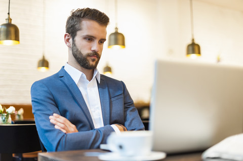 Geschäftsmann schaut auf Laptop in einem Café, lizenzfreies Stockfoto