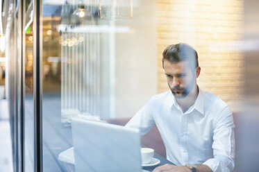 Businessman using laptop in a cafe - DIGF01274