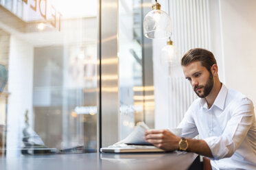 Businessman reading newspaper in a cafe - DIGF01277