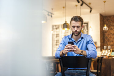 Young man looking at cell phone in a cafe - DIGF01281