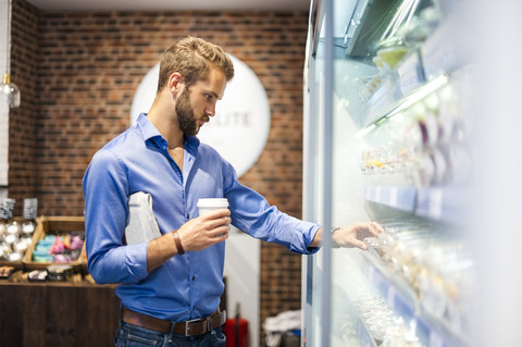 Young man choosing food from cooling shelf in a coffee shop stock photo