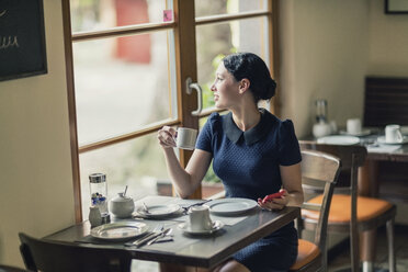Junge Frau in einem Café schaut aus dem Fenster - TAMF00659