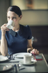 Junge Frau trinkt Kaffee in einem Cafe - TAMF00661