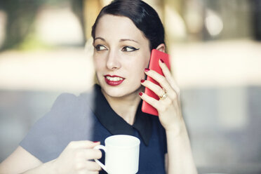 Junge Frau telefoniert mit Handy in einem Café - TAMF00663