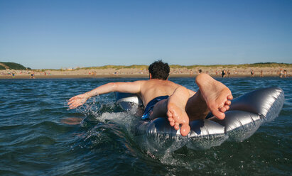 Mann auf Luftmatratze liegend schwimmt im Meer - DAPF00353