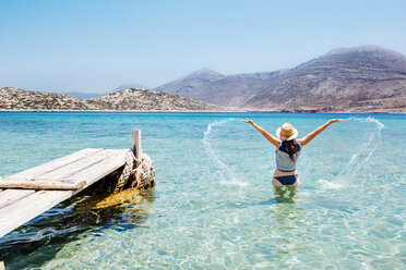 Griechenland, Kykladen-Inseln, Amorgos, Frau planscht im blauen Wasser der Ägäis neben einem Holzsteg - GEMF01026