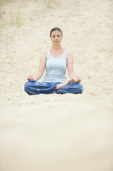 Woman with closed eyes relaxing in Lotus position in sand - MAEF12027