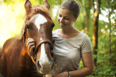 Lächelnde junge Frau mit Pferd - MAEF12037