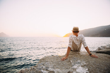 Greece, Cylcades Islands, Amorgos, man enjoying the sunset next to the sea - GEMF01036