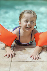 Porträt eines kleinen Mädchens mit Schwimmreifen am Beckenrand - SHKF00683
