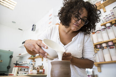 Woman enameling a ceramic mug - ABZF01254