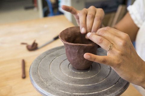 Frau bei der Arbeit mit Ton in einer Keramikwerkstatt, lizenzfreies Stockfoto