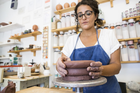 Frau bei der Arbeit mit Ton in einer Keramikwerkstatt, lizenzfreies Stockfoto